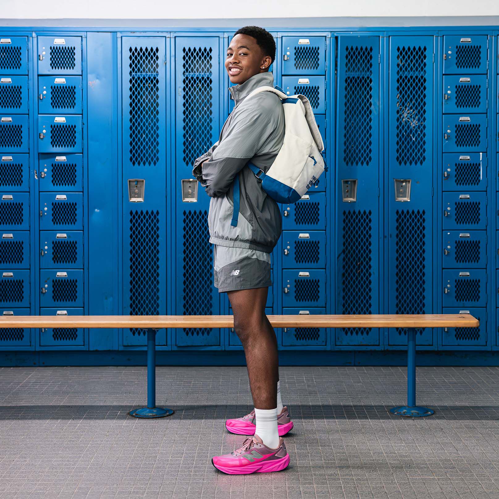 Quincy Wilson wearing the FuelCell Rebel shoes running and waving at a hallway. 